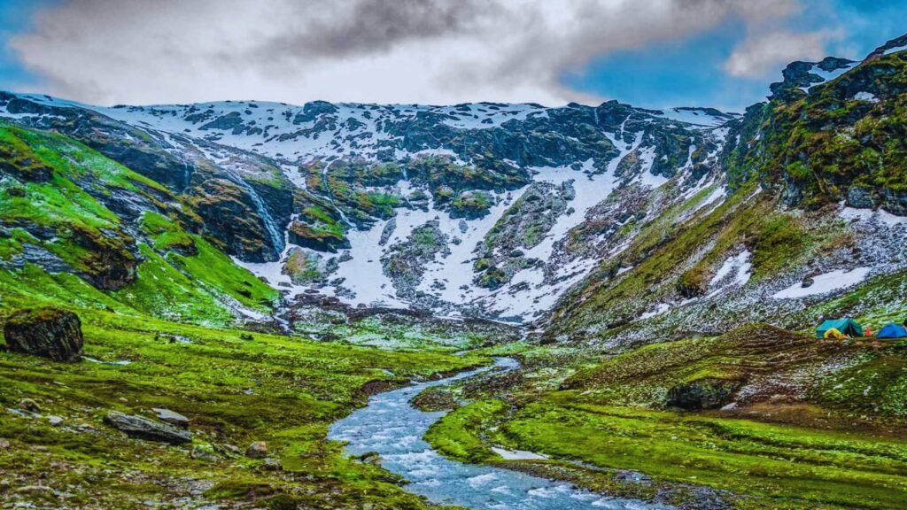 Trekkers hiking through lush alpine meadows on the Bhrigu Lake Trek